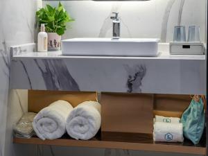 a bathroom with a sink and towels on a shelf at LanOu Hotel Nanyang Wancheng Guangwu Emperor City in Nanyang