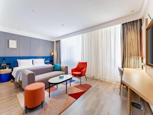 um quarto de hotel com uma cama e uma cadeira vermelha em LanOu Hotel Hohhot New Town Moore City em Hohhot