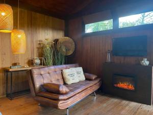 a leather couch in a living room with a fireplace at Pine Lodge - direct train to Porto in Valongo