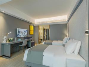 a bedroom with a large white bed and a desk at LanOu Hotel Linyi Lanshan Lushang Center Wanda Plaza in Linyi