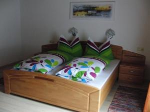 a bed with a wooden frame with pillows on it at Haus Lärchenhof in Holzgau