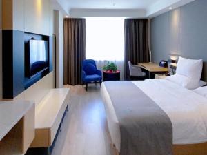 LanOu Hotel Golmud Middle Bayi Road في Golmud: غرفة في الفندق بها سرير ومكتب وتلفزيون