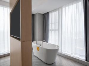 a bathroom with a white tub in front of a window at LanOu International Hotel Rizhao University Town in Rizhao