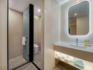 uma casa de banho com um lavatório, um espelho e um WC. em LanOu Hotel Linyi Railway Station National Fitness Center em Linyi