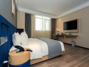 ein Hotelzimmer mit einem Bett und einem Flachbild-TV in der Unterkunft LanOu Hotel Huai'an Jinhu Suning Plaza West Health Road in Jinhu
