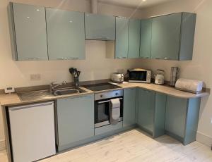 a kitchen with blue cabinets and a sink and a microwave at Alsager Town Centre Apartment in Alsager