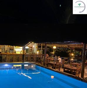 a swimming pool with people sitting at a restaurant at night at Shamba Village in Paje