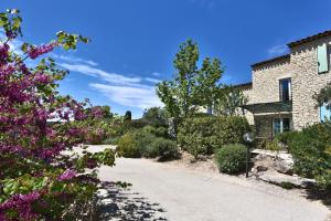a driveway leading to a house with purple flowers at Le Bastidon de Guillemette in Gordes