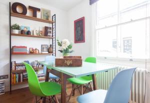 倫敦的住宿－NAVAL COTTAGE IN THE HEART OF ROYAL GREENWICH，一间带桌子和绿色椅子的用餐室