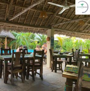 a group of people sitting at tables in a restaurant at Shamba Village in Paje