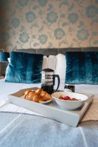 a tray of croissants and a bowl of strawberries on a bed at Blue Anchor House in Maryport