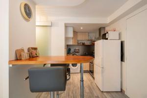 eine Küche mit einem Holztisch und einem Kühlschrank in der Unterkunft L'Ainstant in Bellegarde-sur-Valserine