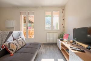 ein Wohnzimmer mit einem Sofa und einem Flachbild-TV in der Unterkunft L'Ainstant in Bellegarde-sur-Valserine