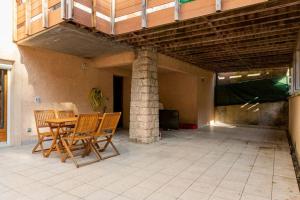 eine Terrasse mit einem Tisch, Stühlen und einer Säule in der Unterkunft L'Ainstant in Bellegarde-sur-Valserine