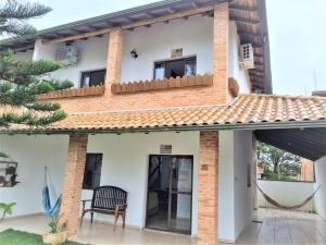 een huis met een balkon en een stoel bij Casa Conforto! A sua casa de praia em Itapoá - SC in Itapoa