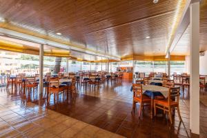 um restaurante com mesas e cadeiras de madeira e janelas em Salou Pacific Rentalmar em Salou