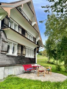 a house with a picnic table and chairs in front of it at Berghüsli Heiterswil in Wattwil