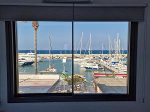 ein Fenster mit Blick auf einen Yachthafen mit Booten in der Unterkunft The Belvedere Latchi Marina in Lachi