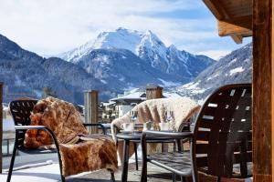 a table and chairs on a balcony with a view of mountains at Huber's Boutique Hotel in Mayrhofen