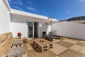 a patio with a table and chairs and an umbrella at Famara Loft 12 in Famara