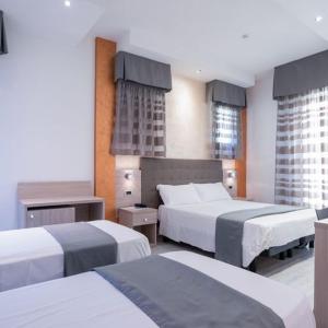 a hotel room with two beds and two windows at Hotel Gabbiano in Rimini