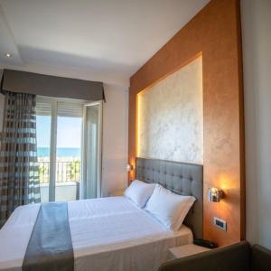 una camera con un grande letto e una finestra di Hotel Gabbiano a Rimini