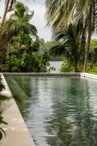 een zwembad met palmbomen en een waterlichaam bij Kurulu Bay in Ahangama