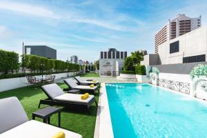 a pool on the roof of a building with lounge chairs at The Quartier Hotel Phromphong - Thonglor by Compass Hospitality in Bangkok