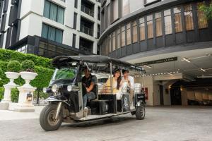 Eine Gruppe von Menschen, die in einem Golfwagen fahren in der Unterkunft The Quartier Hotel Phromphong - Thonglor by Compass Hospitality in Bangkok