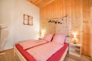 a bed in a room with a wooden wall at Grushof App Köpfl in Sluderno