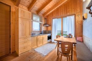 uma cozinha com armários de madeira e uma mesa com cadeiras em Grushof App Köpfl em Sluderno