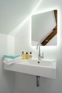 ein Badezimmer mit einem weißen Waschbecken und einem Spiegel in der Unterkunft B&B aan de Koningsmuur in Dieren