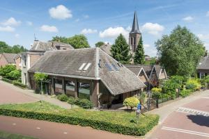 a house with a roof on a street with a church at B&B aan de Koningsmuur in Dieren