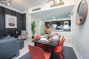 une salle à manger et un salon avec une table noire et des chaises rouges dans l'établissement Deluxe 21st Flr Huge 3BR Pool & Gym Near Mall, à Dubaï