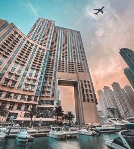 Address Dubai Marina Residences by Qstay في دبي: مبنى كبير فيه قوارب في الماء وطائرة