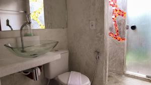 y baño con lavabo de cristal sobre un aseo. en Pousada Aroeira, en Caraíva