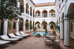 ein Innenhof mit Stühlen und einem Pool in einem Gebäude in der Unterkunft Equity Point Marrakech in Marrakesch