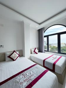 two beds in a room with a window at Rubillion Hotel - 5-Min Walking to Back Beach in Vung Tau