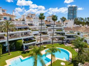 - une vue aérienne sur un bâtiment doté d'une piscine et de palmiers dans l'établissement Magnifico piso en Marbella, à Marbella