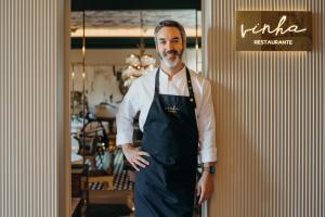 un homme portant une tablier debout dans un restaurant dans l'établissement Vinha Boutique Hotel - The Leading Hotels of the World, à Vila Nova de Gaia