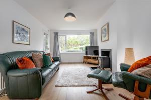 a living room with a green couch and a television at Letham Place - 3 Bedroom House - Sleeps 5 - Log Burner in Fife