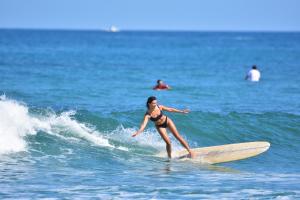 a woman in a bikini riding a wave on a surfboard at SURF HOSTEL BIARRITZ in Biarritz