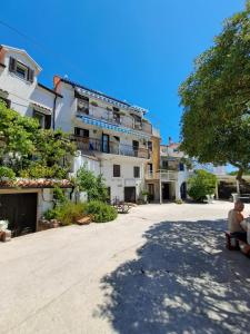 two people sitting on a bench in front of a building at Apartment Borna in Baška