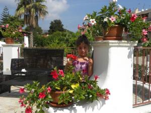 Una bambina in piedi accanto a delle piante in vaso. di Hotel Borgo Eolie a Città di Lipari