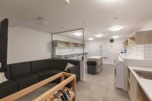 uma sala de estar com um sofá preto numa cozinha em 2BR Mason Square @ Moonee Ponds em Melbourne