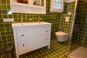 a bathroom with a white sink and green tiles at Chambre d'hôtes et Spa en Luberon in Volx