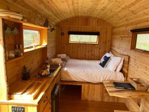a small bedroom with a bed in a log cabin at Orchard retreat off grid shepherds huts in Dorset in Dorchester