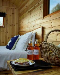 two bottles of sauce on a table next to a bed at Orchard retreat off grid shepherds huts in Dorset in Dorchester