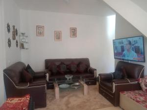 een woonkamer met 2 leren banken en een tv bij Les jardaine d'ifrane in Ifrane