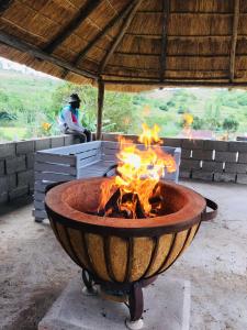 a fire pit with flames in it with a person in the background at Ndlovu Palace in Ragbubee